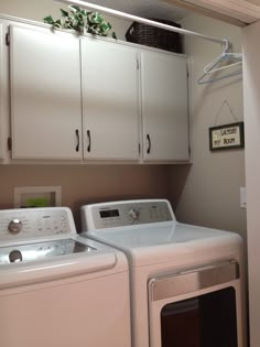 a washer and dryer in a room with white cupboards on the wall