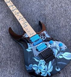 an electric guitar with blue flowers painted on it's body is laying on the floor