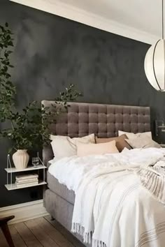 a bedroom with a bed, nightstands and plants on the side of the bed