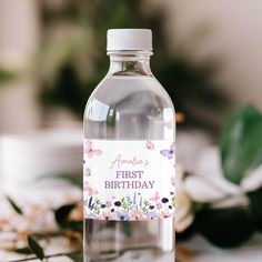 a bottle of water with an empty label on it sitting on a table next to flowers