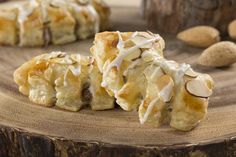 some kind of pastry that is sitting on a wooden table with almonds around it