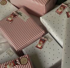 several wrapped presents sitting on top of each other next to a christmas tree with red and white stripes