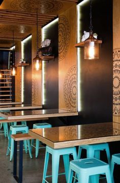 an empty restaurant with wooden tables and blue stools