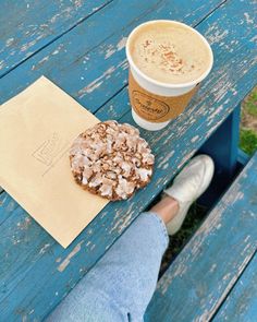 a doughnut sitting on top of a blue picnic table next to a cup of coffee