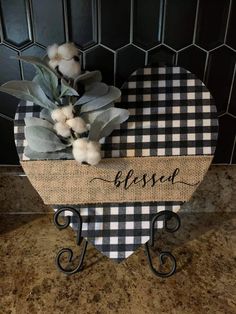 a black and white checkered heart shaped sign with cotton flowers on it that says, blessed