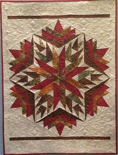 a quilted wall hanging with red and green leaves on the bottom, in front of a blue wall