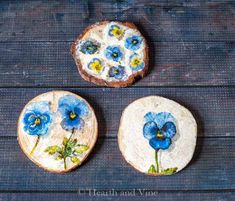 three pieces of bread with blue flowers painted on them sitting on a wooden table top