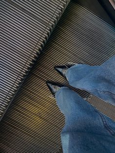 a person wearing blue jeans and black shoes standing next to a metal radiator