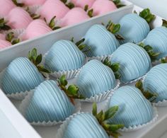 there are many blue and pink chocolates in the box with strawberries on top