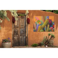 a painting on the side of a building next to a potted plant and door