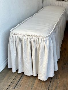 a white bed sitting on top of a wooden floor next to a wall and window