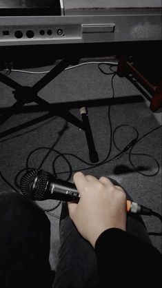 a person holding a microphone in front of a keyboard and sound equipment on the floor