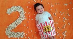 a baby is laying down with popcorn buckets in front of her and number 2