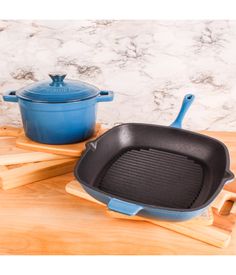 a blue cast iron skillet sitting on top of a wooden cutting board next to an oven