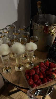 strawberries and champagne are sitting on a table next to some glasses with ice in them