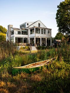 a boat is sitting in the grass near a large white house with two storys