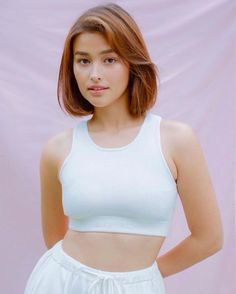 a woman in white top and shorts posing for the camera with her hands on her hips