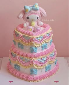 a pink and blue cake with a stuffed animal on it's top tiers