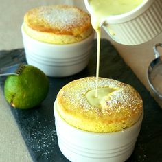 two small white bowls filled with food on top of a black tray next to a lime