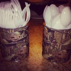 two tin cans filled with white utensils on top of a counter