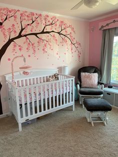 a baby's room decorated in pink and white with a tree painted on the wall