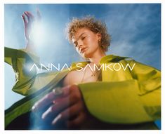 a woman in a yellow dress is holding her hand up to the sky and looking down