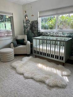 a baby's room with a crib, chair and rug in front of the window