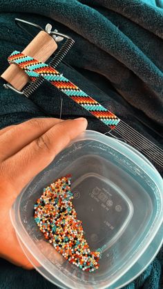 a person holding a plastic container with beads on it and a comb in the other hand