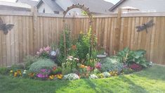 a garden with lots of flowers in the middle of it and a wooden fence behind it