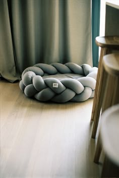 a dog bed that is on the floor in front of a window