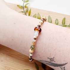 🍄earthy cottagecore beaded mushroom bracelet  🍁comes in 3 different lengths, 7 in, 8 in, 9 in, perfect for layering!  ☕️a great gift idea for anyone who loves mushrooms or the outdoors!  ---------------------------------------------- Check out our other bracelets here: https://needfulthingsthrift.etsy.com?section_id=46789369 Check out the matching necklace!  https://needfulthingsthrift.etsy.com/listing/1755288206 M A T E R I A L S artist lampwork glass beads, natural stone beads, beading wire, lobster clasp Please note, this item is handmade and may be slightly different each time it is made, But I assure that it is very close to what you see in photos All jewelry is handmade with love, designed and created by us. We are lovers of jewelry and fashion, that is why we put so much effort in Earthy Cottagecore, Beaded Mushroom, Mushroom Bracelet, Aesthetic Whimsical, Mushroom Gifts, Cottagecore Mushroom, Fairycore Aesthetic, Cute Mushroom, Jewelry Cute