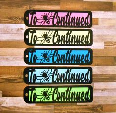 four different colored tags with the words, to continue and to continue on them are lined up against a wooden background