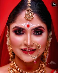 a woman with makeup and jewelry on her face, wearing a red veil over her head