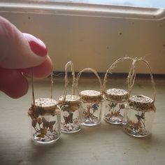 small glass vases with flowers in them are being held by someone's hand