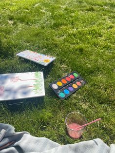 a person laying in the grass with their feet on the ground next to some art supplies