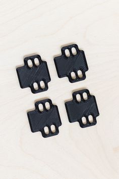 four pieces of black plastic sitting on top of a wooden table