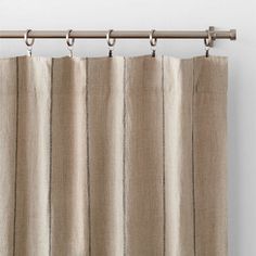 a beige curtain hanging on the side of a window with metal rods and an iron rod