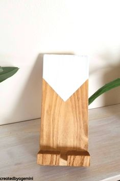 a wooden object with white paint on it sitting on a table next to a plant