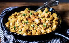 a black bowl filled with macaroni and cheese on top of a wooden table