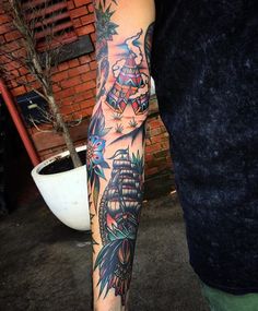 a man's arm with tattoos on it and an image of a ship in the background