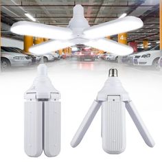 two white ceiling fans in a parking garage with cars parked behind them and an overhead fan