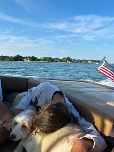 two people in a boat with a dog on their lap and an american flag flying above them