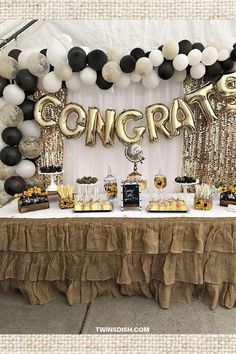 a table with balloons, sunflowers and confetti on it in front of a sign that says congrat