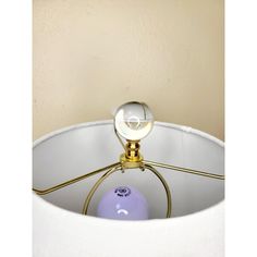 a lamp that is sitting on top of a white table cloth with a purple ball in it