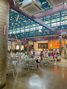 people are sitting at tables in the middle of an open area with exposed ceilings and metal beams