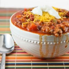 a white bowl filled with chili and cheese