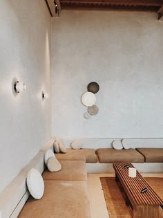 a living room filled with lots of furniture next to a wall mounted light above a wooden coffee table