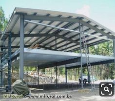 a large metal structure sitting on top of a dirt field next to a tree filled forest