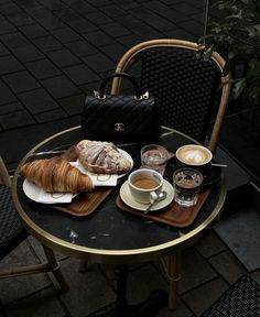 a table with coffee, croissants and a handbag sitting on it