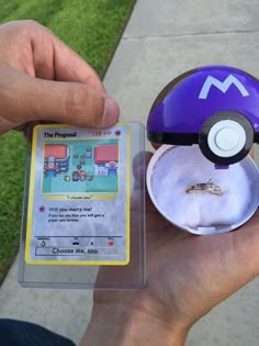 someone is holding a pokemon card with a ring on it's finger and an object in the other hand